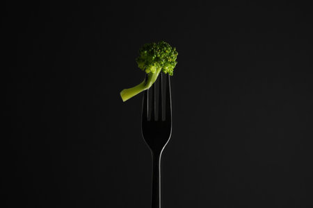 Fork with tasty broccoli on black backgroundの写真素材
