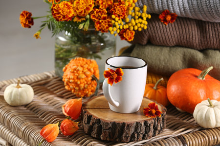 Beautiful autumn composition with cup of drink and pumpkins on wicker tableの写真素材