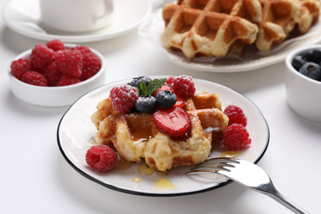 Delicious Belgian waffle with fresh berries and honey served on white tableの写真素材