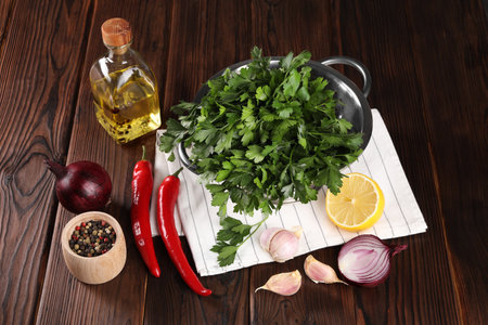 Colander with fresh parsley, spices and other products on wooden tableの写真素材