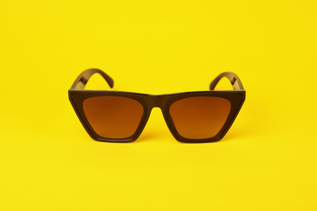 Stylish pair of sunglasses on yellow backgroundの写真素材