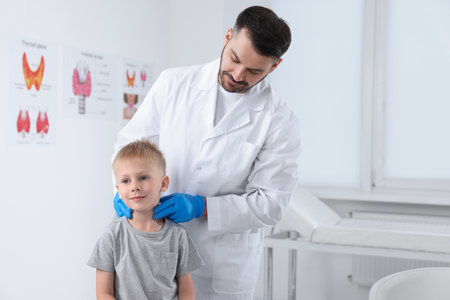 Endocrinologist examining boy's thyroid gland at hospital