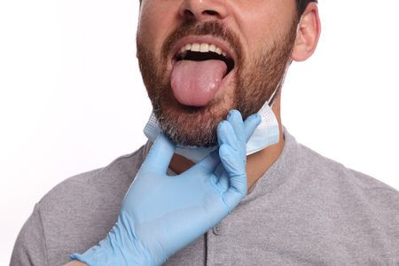 Doctor examining man`s oral cavity on white background, closeupの写真素材