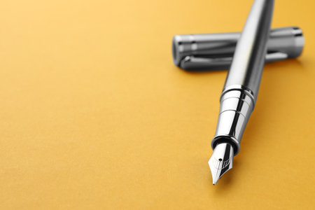 Stylish fountain pen with cap on yellow background, closeup. Space for textの写真素材