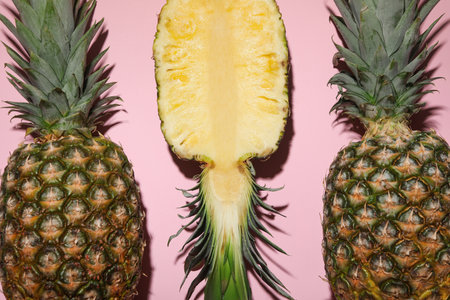 Whole and cut ripe pineapples on pale pink background, flat layの写真素材