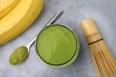 Glass of tasty matcha smoothie on light gray table, flat layの写真素材