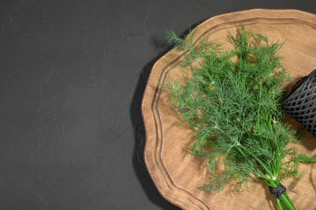Bunch of fresh dill and spool of thread on gray table, top view. Space for text