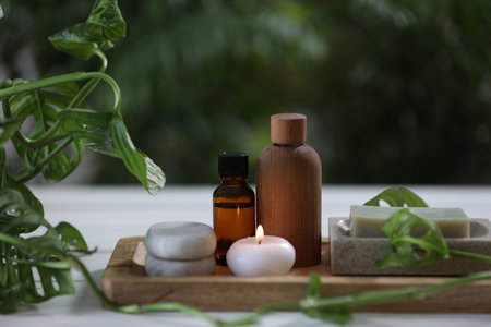 Beautiful composition with different spa products and green leaves on white table, closeupの写真素材