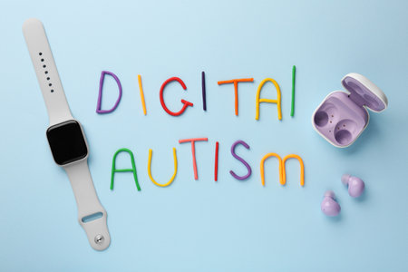 Phrase Digital Autism made of colorful plasticine, smartwatch and earphones on light blue...