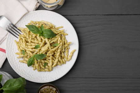 Plate of delicious trofie pasta with pesto sauce and basil leaves on gray wooden table, flat lay. Space for textの写真素材