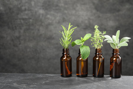 Bottles with essential oils and plants on gray textured table. Space for textの写真素材