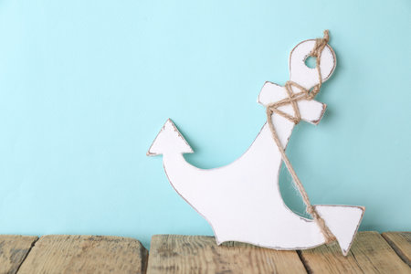 Anchor with hemp rope on wooden table near turquoise wall, space for textの写真素材