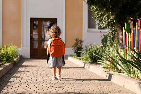 Little girl walking to kindergarten outdoors on sunny day, back view. Space for textの写真素材