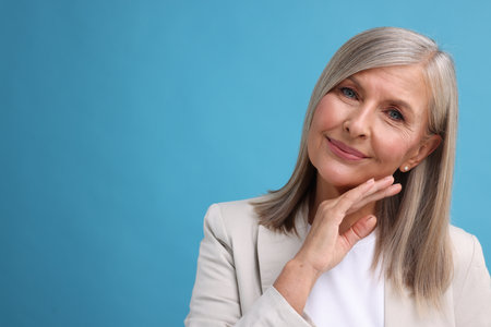 Portrait of beautiful middle aged woman on light blue background, space for textの写真素材