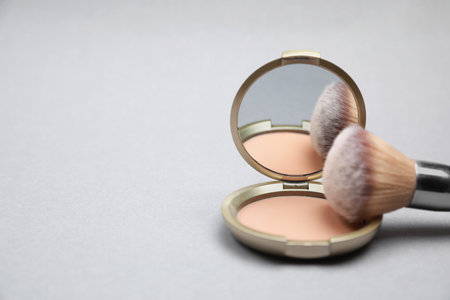 Face powder and brush on light gray background, closeup. Space for textの写真素材