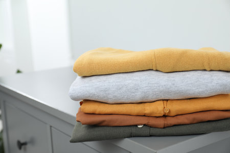 Sorting and organizing. Different folded clothes on chest of drawers indoors, space for textの写真素材