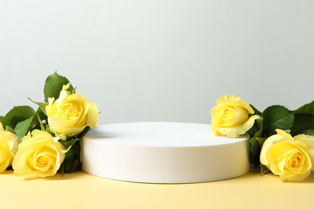 Beautiful presentation for product. Round podium and yellow roses on beige table against light gray background, space for textの写真素材
