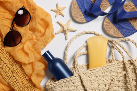 Flat lay composition with wicker bag and other beach accessories on white background