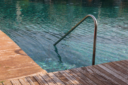 Swimming pool, metal rail and wooden deck at luxury resort