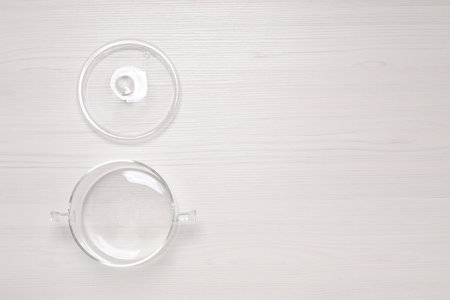 Empty glass pot and lid on white wooden table, flat lay. Space for textの写真素材