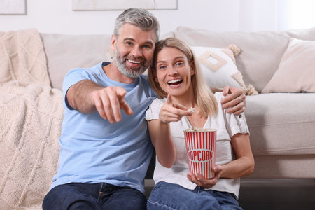 Happy affectionate couple with popcorn spending time together at home. Romantic dateの写真素材