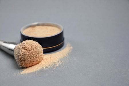 Loose face powder and makeup brush on light gray background, closeup. Space for textの写真素材