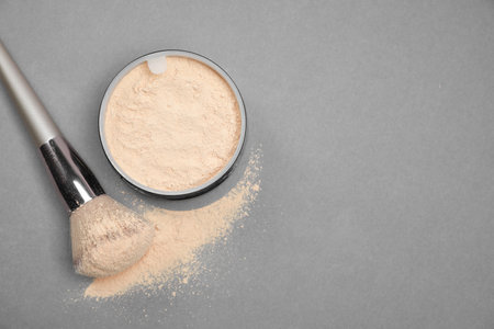 Loose face powder and makeup brush on light gray background, flat lay. Space for text