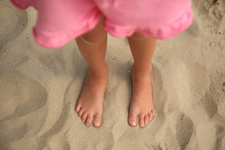 Little girl standing on sandy beach, closeupの写真素材