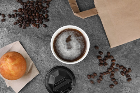 Coffee to go. Paper cup with tasty drink, muffin and beans on gray table, flat layの写真素材