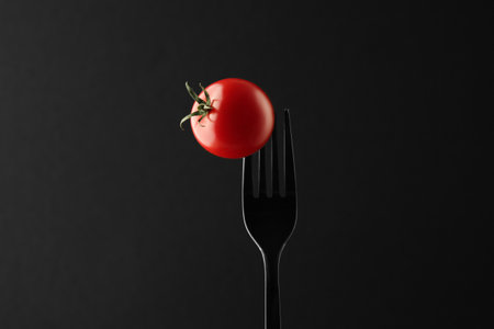 Fork with cherry tomato on black backgroundの写真素材