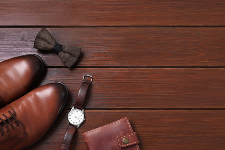 Stylish brown bow tie, shoes, wristwatch and wallet on wooden background, flat lay. Space for textの写真素材