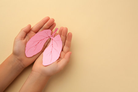 Child holding paper human lungs on beige background, top view. Space for textの写真素材