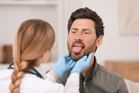 Doctor in gloves examining man`s oral cavity indoorsの写真素材