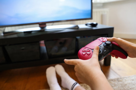 Child playing video games with controller at home, closeup