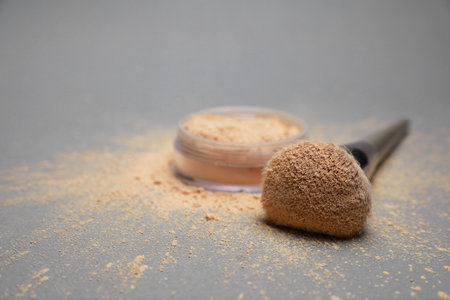 Loose face powder and makeup brush on light gray background, closeup. Space for textの写真素材