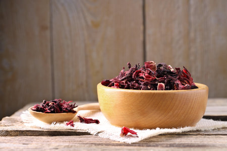 Dry hibiscus tea in bowl on wooden table, space for textの写真素材