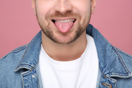 Man showing his tongue on pink background, closeupの写真素材