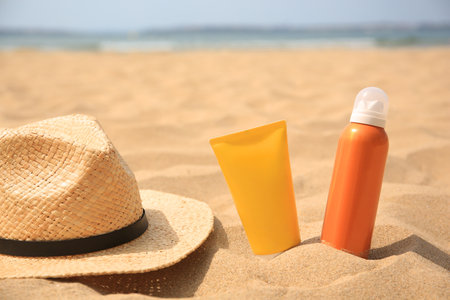 Sunscreens and straw hat on sandy beach, space for text. Sun protectionの写真素材