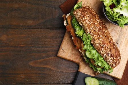 Delicious sandwich with schnitzel on wooden table, top view. Space for textの写真素材