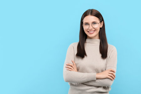Portrait of smiling woman in stylish eyeglasses on light blue background. Space for textの写真素材