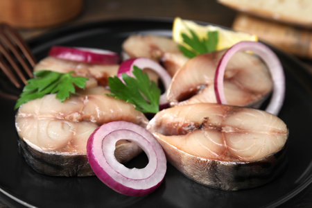 Slices of tasty salted mackerel, onion rings and parsley on black plate, closeupの写真素材