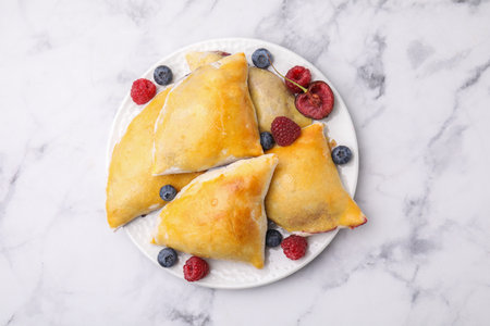 Delicious samosas with cherry and berries on white marble table, top viewの写真素材