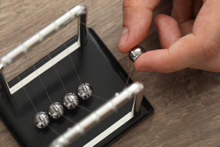 Man playing with Newton's cradle at wooden table, above view. Physics law of energy conservationの写真素材