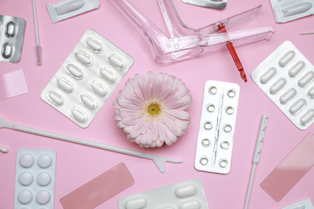 Many gynecological tools, pills and gerbera flower on pink background, flat layの写真素材