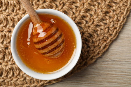 Dipper with honey in bowl on wooden table, top view. Space for textの写真素材