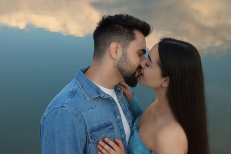 Romantic date. Beautiful couple kissing near lakeの写真素材