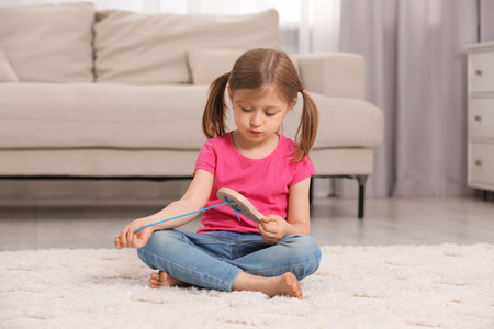 Cute little girl playing with wooden lacing toy indoorsの写真素材