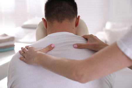 Man receiving massage in modern chair indoors, closeupの写真素材