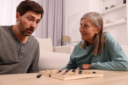 Family playing checkers at wooden table in roomの写真素材