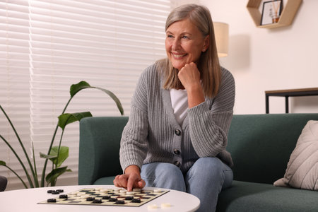 Happy senior woman playing checkers at homeの写真素材